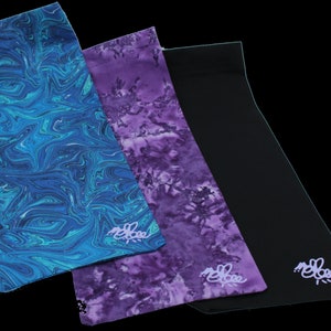 May include: Three fabric headbands in different patterns. One is blue with a swirling marble pattern, one is purple with a swirling marble pattern, and one is black. All three headbands have the word "melbee" embroidered on them in a light purple color.