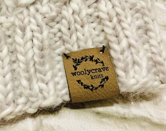 May include: White knitted beanie with a brown leather tag that says "woollycrave knits".