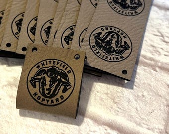 May include: A stack of brown leather tags with black text and a black sheep graphic. The text reads "Whitefield Hopyard".