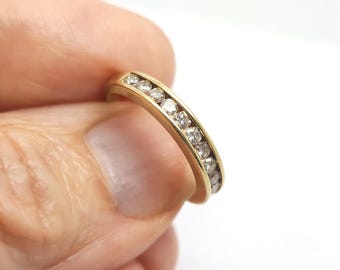 May include: A gold band ring with a row of small diamonds set in the band.