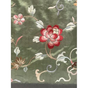 May include: Green fabric with embroidered flowers in shades of pink, red, and white. The flowers are arranged in a floral pattern with vines and leaves.