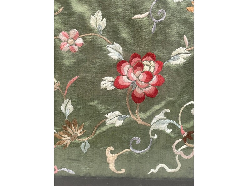 May include: Green fabric with embroidered flowers in shades of pink, red, and white. The flowers are arranged in a floral pattern with vines and leaves.