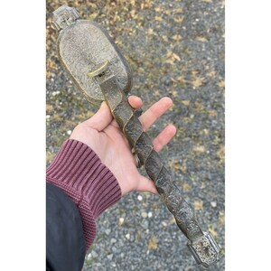 May include: A vintage, ornate, metal door handle with a twisted, decorative stem. The handle is made of a dark, aged metal with a worn finish.