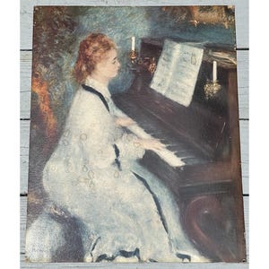 May include: A painting of a woman in a white dress playing a piano. The piano is brown and has a sheet of music on it. There are two candlesticks on the piano, each with a lit candle.