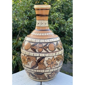 May include: A brown and white ceramic vase with a round body and a narrow neck. The vase is decorated with a floral pattern in brown and black.
