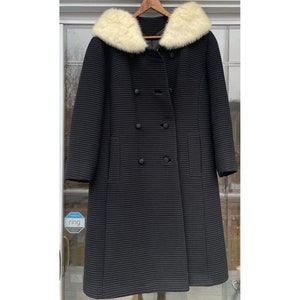 May include: A black double-breasted coat with a white faux fur collar. The coat has a ribbed texture and is lined with a black fabric.