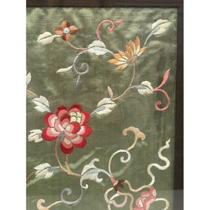 May include: A framed green silk embroidery with floral designs in shades of pink, red, white, and yellow. The embroidery features delicate flowers and leaves.