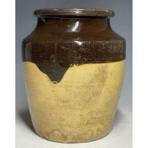 Peut inclure: Un pot en céramique émaillée brun et jaune avec un corps arrondi et une large ouverture.