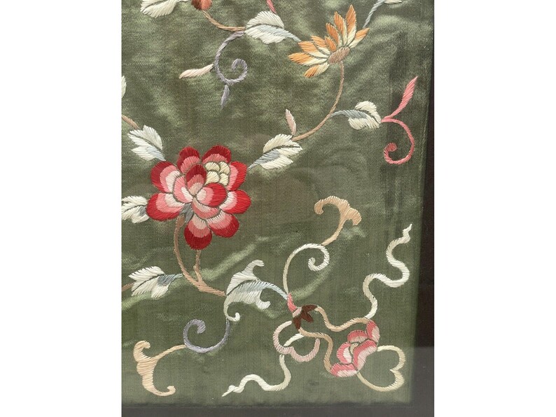May include: A green fabric with embroidered flowers in shades of pink, red, and white. The flowers are arranged in a floral pattern with delicate vines.