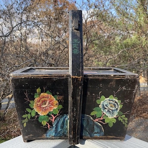 May include: A black wooden box with a hinged lid and a carrying handle. The box is decorated with painted flowers and the Chinese characters "財神到" which translates to "God of Wealth Arrives".