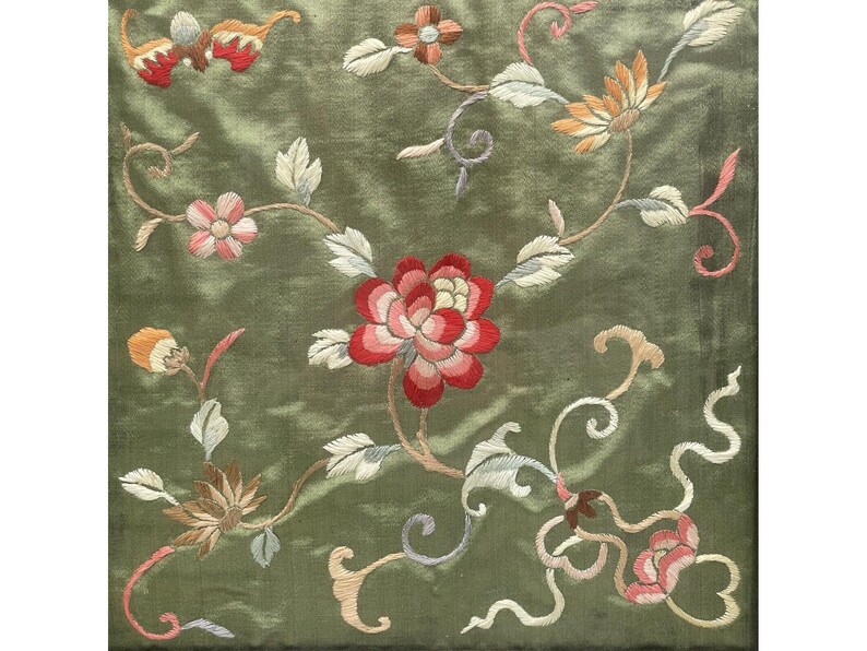 May include: A green fabric with embroidered floral designs in shades of pink, red, white, and yellow. The flowers are arranged in a repeating pattern on the fabric.