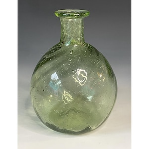 Könnte beinhalten: Eine klare, grün getönte Glasflasche mit rundem Körper und schmalem Hals. Die Flasche hat ein leicht gewirbeltes Design und ist mit kleinen Blasen gefüllt. Die Flasche wird wahrscheinlich zu dekorativen Zwecken verwendet.