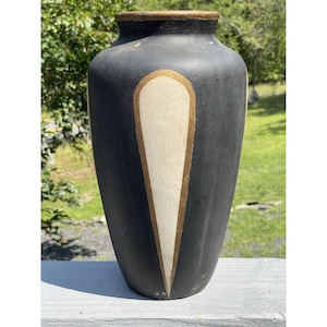 May include: Black ceramic vase with a white and gold geometric design. The vase has a rounded shape and a smooth finish.