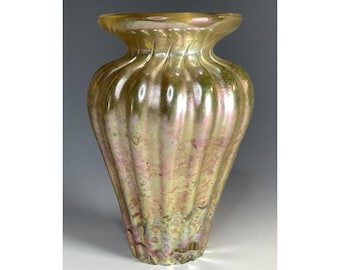 May include: A gold iridescent glass vase with a ribbed design. The vase has a rounded body and a flared opening.