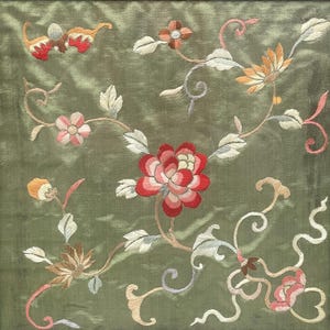 May include: A green silk fabric with embroidered floral designs in shades of red, pink, white, and yellow. The flowers are arranged in a delicate pattern on the fabric.