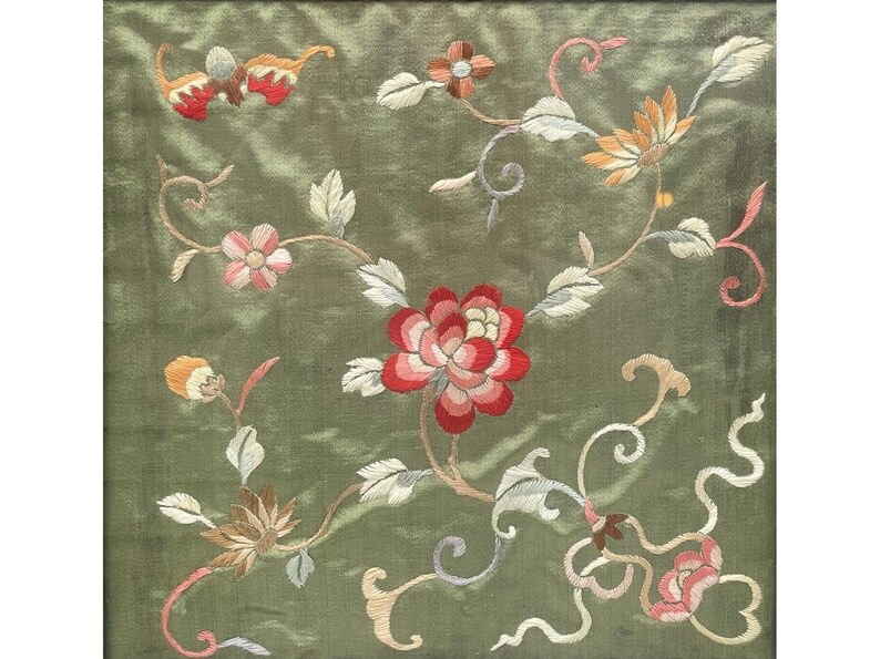 May include: A green silk fabric with embroidered floral designs in shades of red, pink, white, and yellow. The flowers are arranged in a delicate pattern on the fabric.
