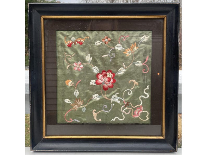 May include: A framed embroidered artwork featuring a floral design with pink, red, and white flowers on a green background.