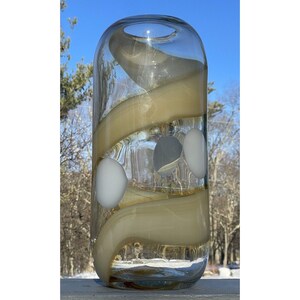 May include: A clear glass vase with a swirl design in beige and white. The vase has a cylindrical shape and is approximately 10 inches tall.