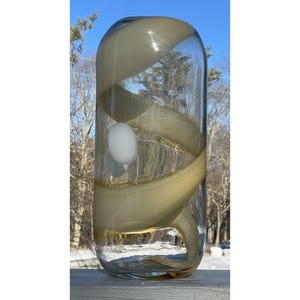 May include: A clear glass vase with a swirling, opaque, cream-colored design. The vase has a round, cylindrical shape.