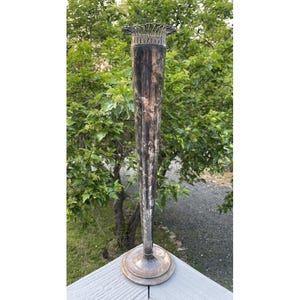 Könnte beinhalten: Eine hohe, silberne Vintage-Vase mit geriffeltem Design und einem dekorativen oberen Rand. Die Vase ist angelaufen und hat eine dunkle Patina.