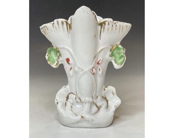 Könnte beinhalten: Eine weiße Porzellanvase mit floralem Design. Die Vase hat eine Trompetenform mit einer breiten Öffnung und einem schmalen Boden. Das Design zeigt grüne Blätter, rote Blumen und goldene Akzente.