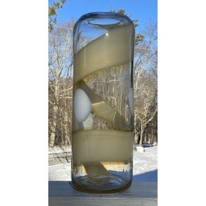 May include: A clear glass vase with a swirling pattern of white and yellow glass. The vase is cylindrical in shape and has a wide mouth.