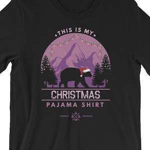 May include: Black t-shirt with a purple mountain scene and a bear wearing a Santa hat. The text "This is my Christmas Pajama Shirt" is printed on the shirt.