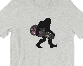 Camiseta Gig Foot: Bigfoot Carrying Rock 'n Roll Guitar Case camiseta unisex de manga corta