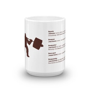 May include: White ceramic mug with a brown silhouette of a Sasquatch lifting a barbell. The mug has a definition of the word "Sasquatch" and its variations printed on it.