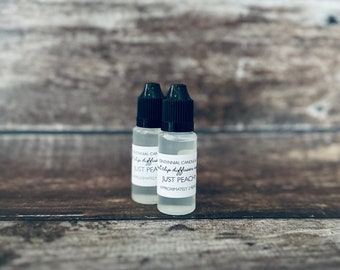 May include: Two small clear glass bottles with black caps. The bottles contain a liquid and have white labels with the text "Just Peach" and "Approximately 2 fl oz".