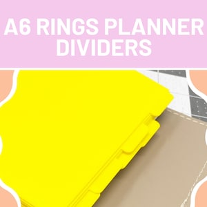 Op de afbeelding: Heldergele A6-ringplannerverdelers met tabbladen, gestapeld tegen een bruinachtige planneromslag. De tekst "A6 Rings Planner Dividers" wordt in witte letters op een roze achtergrond weergegeven.
