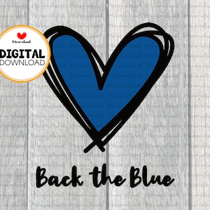 Puede incluir: Un corazón azul con contorno negro y el texto "Back the Blue" sobre un fondo de madera.