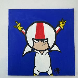 Puede incluir: Una pintura cuadrada sobre fondo azul presenta un personaje de dibujos animados con un casco blanco con una raya roja, un traje blanco y guantes amarillos. El personaje hace un gesto de rock and roll con la mano. La firma del artista está en la esquina inferior derecha.