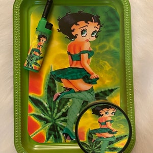 May include: Green metal rolling tray with a cartoon image of a woman in a green dress and a green leaf design. The tray includes a small green lighter and a round container with a matching design.