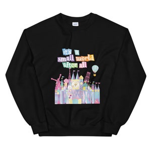 May include: Black sweatshirt featuring a colourful graphic of the "it's a small world" ride at Disney World. The graphic includes the text "it's a small world after all" and a colourful illustration of the ride's facade.
