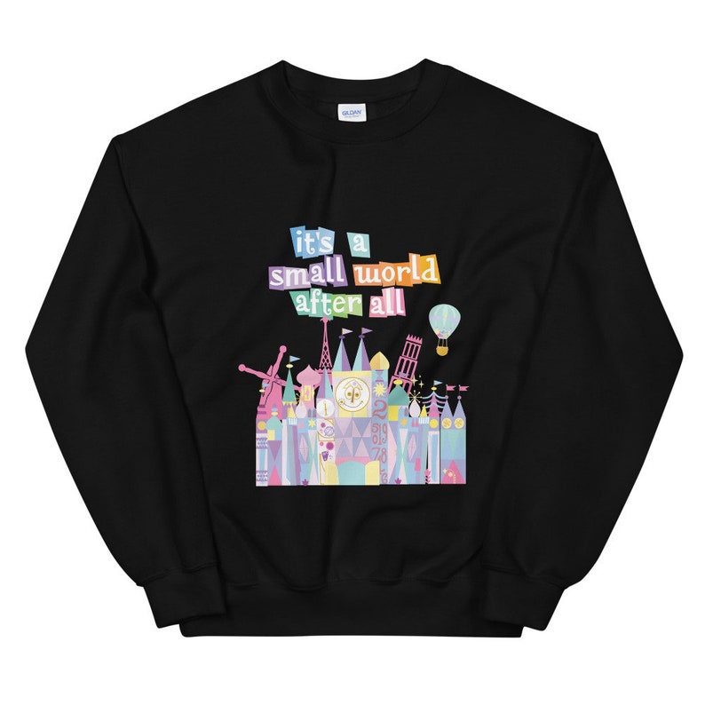 May include: Black sweatshirt featuring a colourful graphic of the "it's a small world" ride at Disney World. The graphic includes the text "it's a small world after all" and a colourful illustration of the ride's facade.