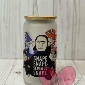 May include: A white frosted glass tumbler with a bamboo lid and a straw. The tumbler features a cartoon illustration of characters from the Harry Potter series, including Severus Snape, Ron Weasley, and Albus Dumbledore. The text "Snape Snape Severus Snape" is printed on the tumbler.