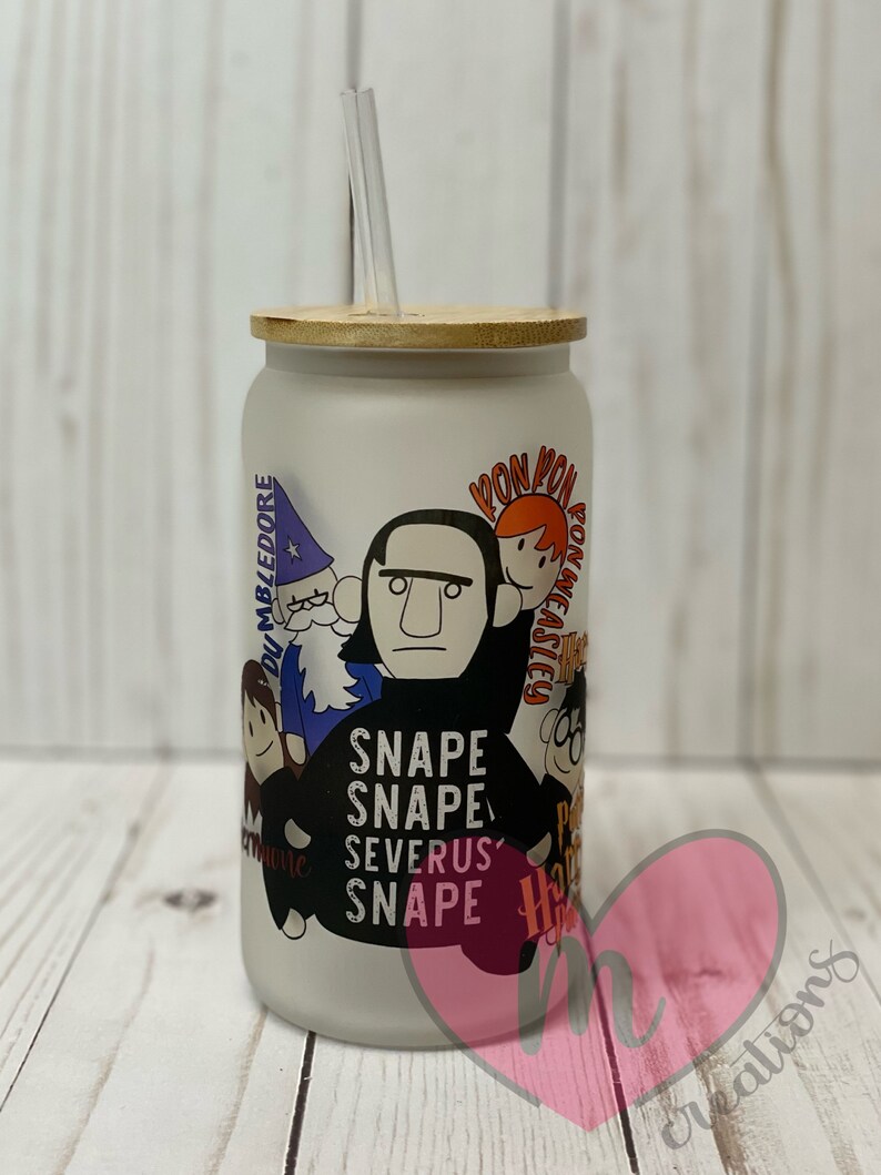 May include: A white frosted glass tumbler with a bamboo lid and a straw. The tumbler features a cartoon illustration of characters from the Harry Potter series, including Severus Snape, Ron Weasley, and Albus Dumbledore. The text "Snape Snape Severus Snape" is printed on the tumbler.
