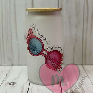 May include: White frosted glass jar with a wooden lid. The jar has a pink heart with the letter "m" inside and a graphic of pink glasses with blue lenses. The text on the jar reads "Don't worry, you're just as sane as me."