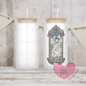 May include: Two white stainless steel tumblers with a wood lid. One tumbler has a graphic of a woman in a crown sitting on a throne with a leafy background. The other tumbler is blank. Both tumblers have a straw.