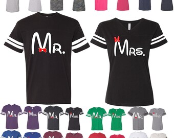 Puede incluir: Camisetas de varios colores con las palabras "Mr." y "Mrs." en letras blancas, con una pajarita o lazo. Las camisetas tienen rayas blancas en las mangas. Disponibles en colores como negro, rosa y verde.