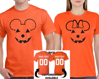 Puede incluir: Dos camisetas naranjas con diseños negros de Mickey Mouse y Minnie Mouse con cara de calabaza. Las camisetas tienen "YOUR TEXT 00" en la parte posterior.