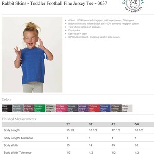 May include: A toddler wearing a blue and white football jersey tee. The jersey has two white stripes on the sleeves and a white yoke. The jersey is available in a variety of colors, including black, granite heather, burgundy, green, heather, hot pink, navy, purple, red, royal, smoke, and white. The size chart shows the finished measurements for sizes 2T, 3T, 4T, and 5/6.