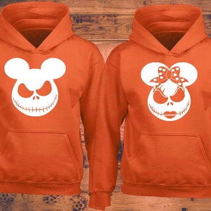 Puede incluir: Dos sudaderas con capucha de color naranja con dise&ntilde;os de Jack Skellington en blanco. Una sudadera con capucha presenta a Jack Skellington con orejas de Mickey Mouse, la otra presenta a Jack Skellington con orejas de Minnie Mouse y un lazo.