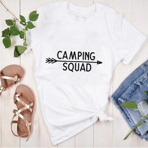 May include: White t-shirt with black text that reads "Camping Squad" and a black arrow pointing to the right.