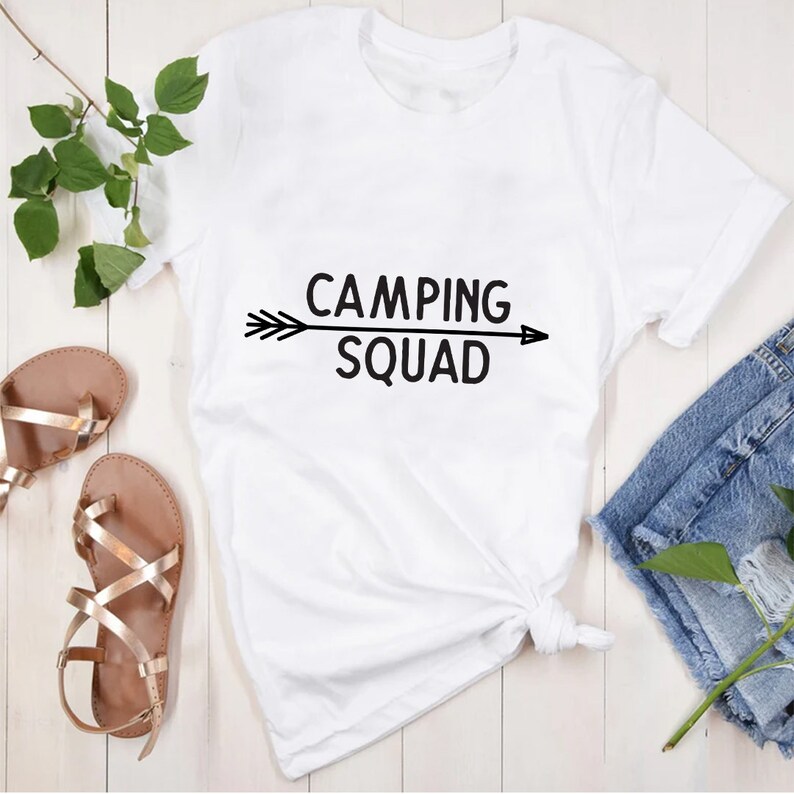 May include: White t-shirt with black text that reads "Camping Squad" and a black arrow pointing to the right.
