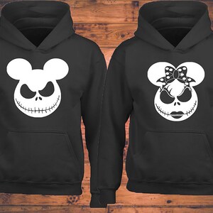 Puede incluir: Dos sudaderas con capucha negras con un gr&aacute;fico blanco de la cara de Jack Skellington con orejas de Mickey Mouse. Una sudadera tiene un lazo en las orejas, la otra no.