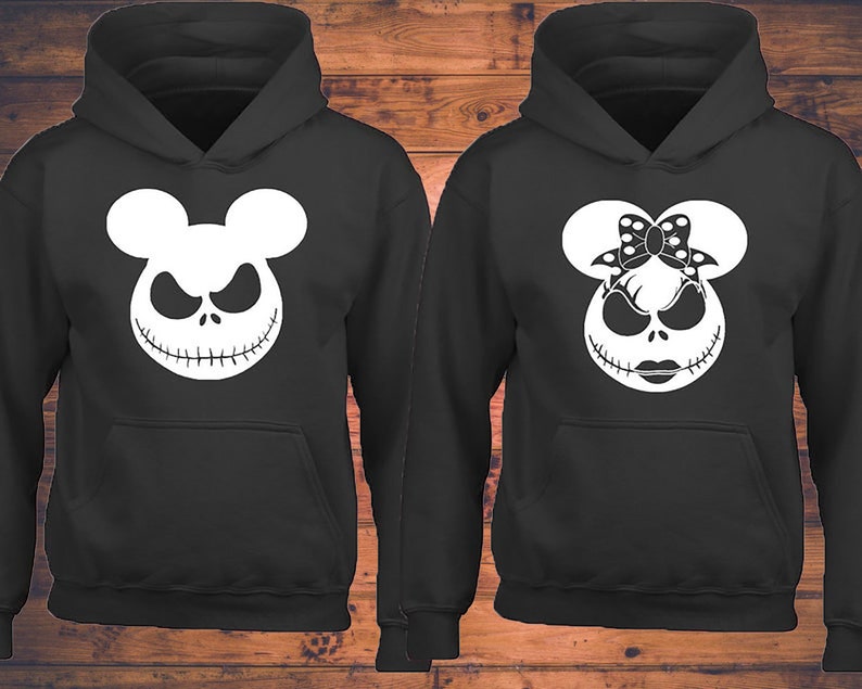 Puede incluir: Dos sudaderas con capucha negras con un gr&aacute;fico blanco de la cara de Jack Skellington con orejas de Mickey Mouse. Una sudadera tiene un lazo en las orejas, la otra no.