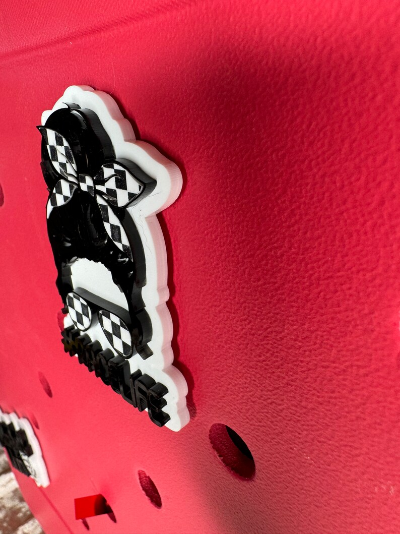 Op de afbeelding: Een witte en zwarte 3D-geprinte sticker met een geruit bandana, een zonnebril en de tekst "#badlife" op een rode achtergrond.