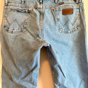 Puede incluir: Vaqueros de mezclilla azul claro con el logo de Wrangler en el bolsillo trasero. Los vaqueros tienen un dise&ntilde;o cl&aacute;sico de cinco bolsillos con corte recto. Los bolsillos traseros presentan costuras en forma de W.